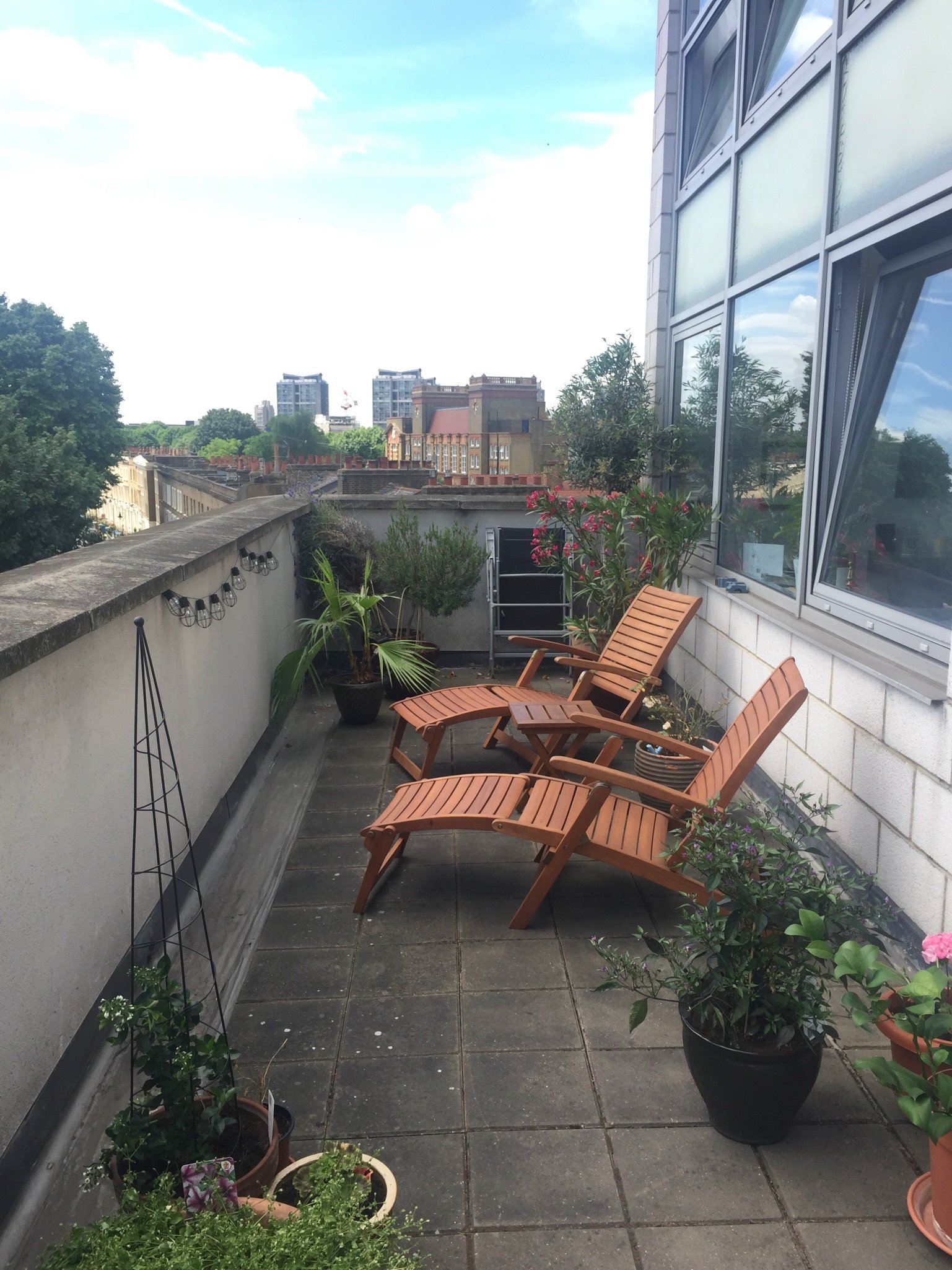 Smaller terrace in summer with teak loungers and planted pots